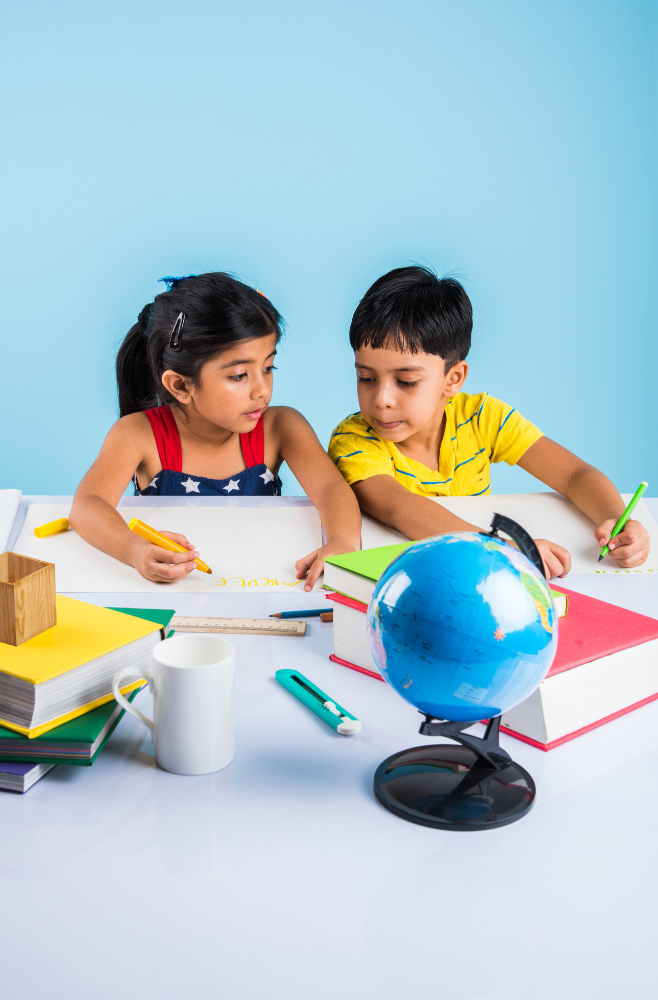 cute-little-indian-asian-kids-studying-study-table-with-pile-books-educational-globe-isolated-light-blue-colour