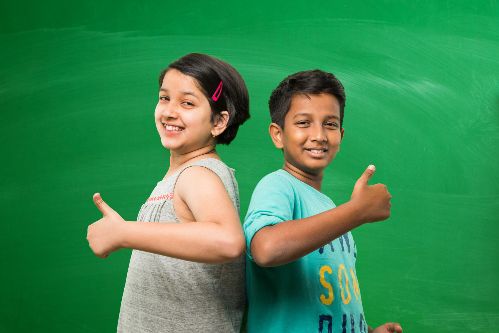 cute-little-indian-asian-school-kids-standing-front-empty-green-chalkboard-background-showing-success-victory-symbol-with-thumbs-up